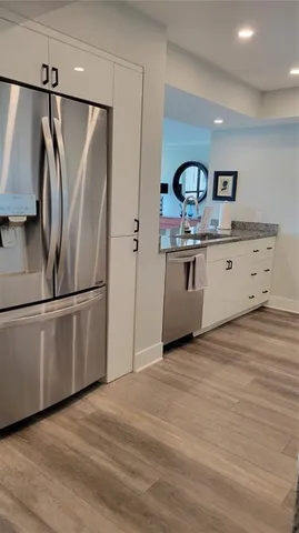 a kitchen with stainless steel appliances granite countertop a refrigerator a sink and white cabinets