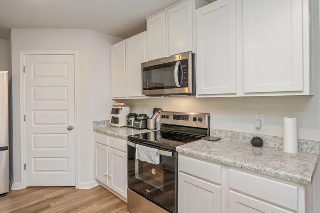a kitchen with granite countertop cabinets stainless steel appliances and wooden floor
