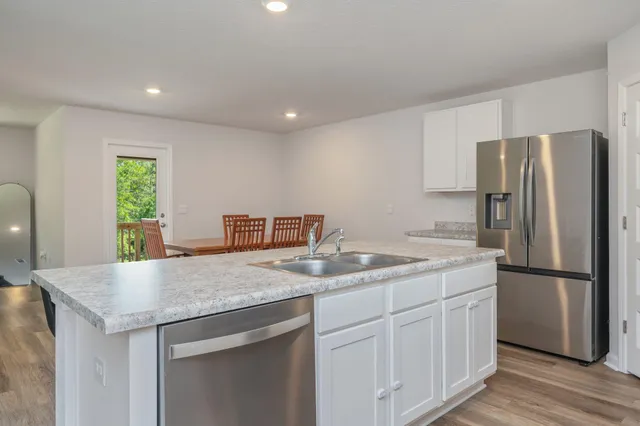 a kitchen with a sink a refrigerator and wooden floor