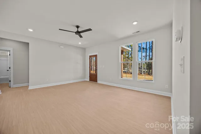 an empty room with windows and ceiling fan