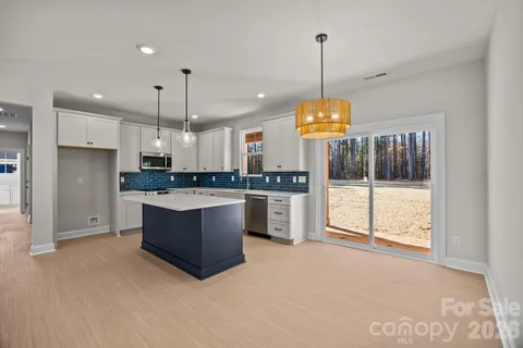 a large kitchen with a refrigerator a stove a oven and a chandelier