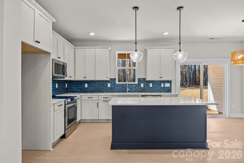 a kitchen with stainless steel appliances granite countertop a sink a stove and a wooden floor