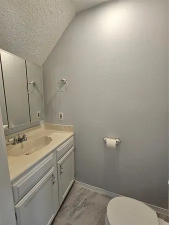 a bathroom with a granite countertop toilet and sink