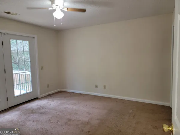 an empty room with a chandelier fan and windows