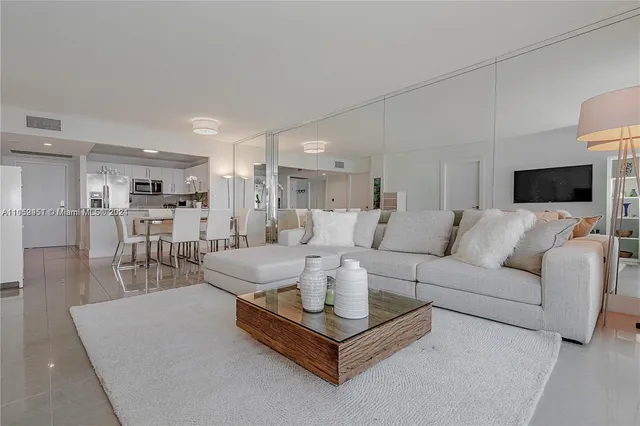 a living room with furniture a flat screen tv and kitchen view