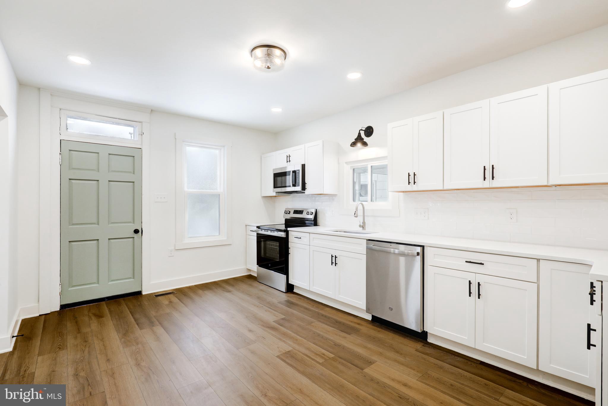 711 Main Street Lykens, PA 17048 - Photo 13 of 38 a kitchen with granite countertop a stove a sink and white cabinets with wooden floor