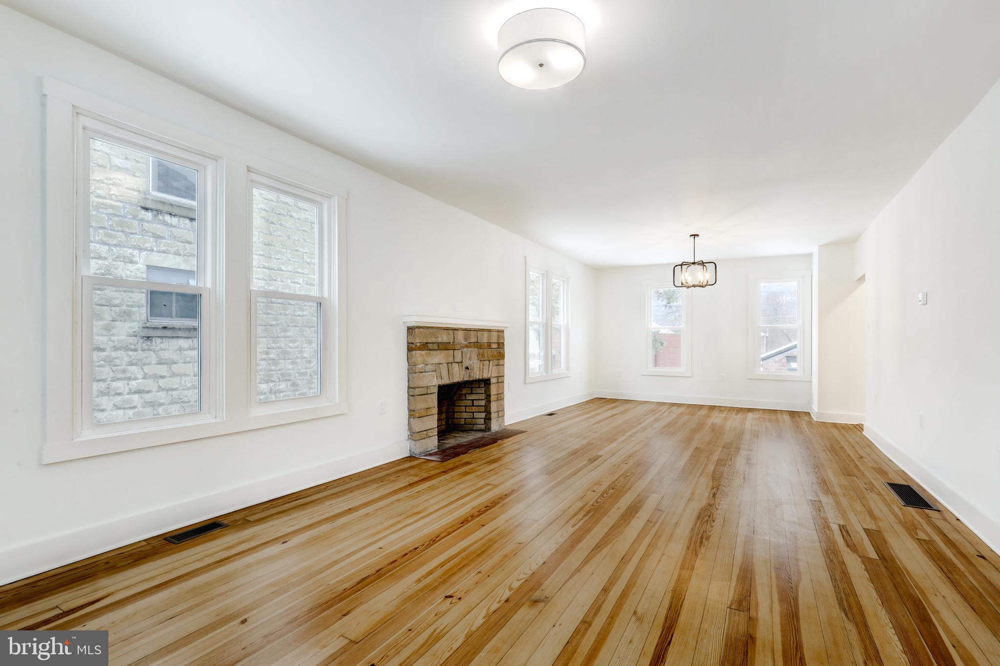 711 Main Street Lykens, PA 17048 - Photo 7 of 38 an empty room with wooden floor fireplace and windows