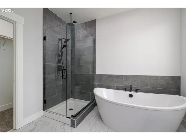 a bathroom with a white bath tub a shower and a sink