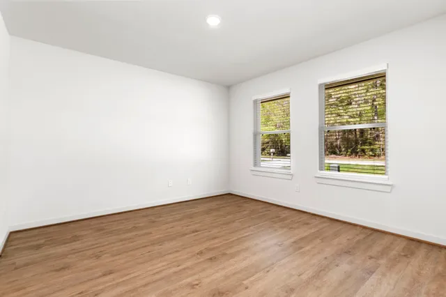 an empty room with wooden floor and windows