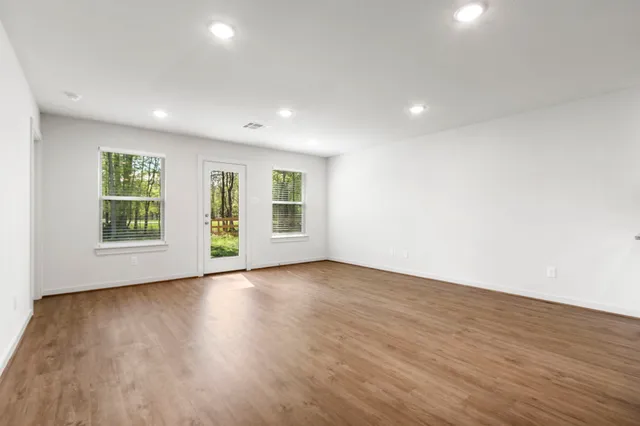 a view of an empty room with wooden floor and a window