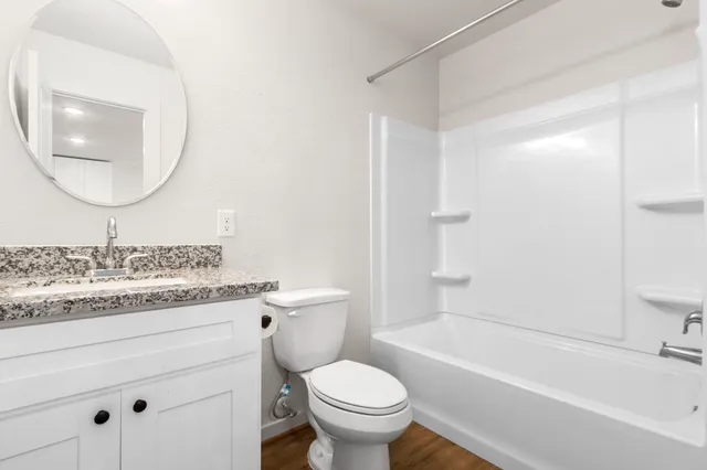 a bathroom with a granite countertop toilet a sink and a mirror