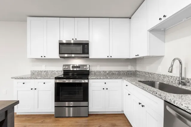 a kitchen with granite countertop white cabinets and stainless steel appliances