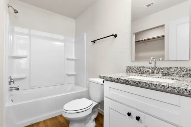 a bathroom with a granite countertop toilet a sink and a bathtub