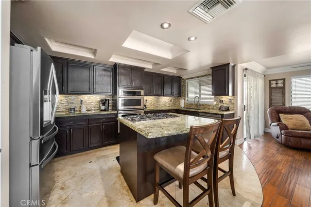a kitchen with stainless steel appliances kitchen island granite countertop a stove refrigerator and cabinets