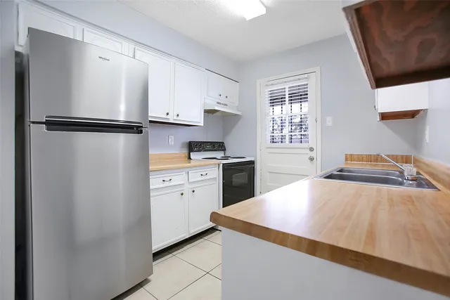 a kitchen with a refrigerator and white cabinets
