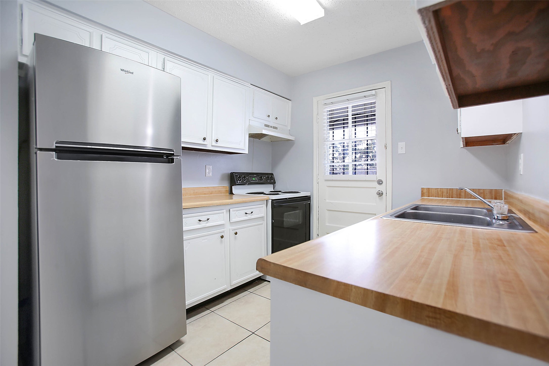 7900 Westheimer Road, Unit 134 Houston, TX 77063 - Photo 12 of 25 a kitchen with a refrigerator and white cabinets