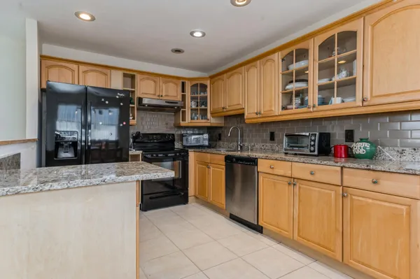 a kitchen with stainless steel appliances granite countertop a stove a sink and a refrigerator