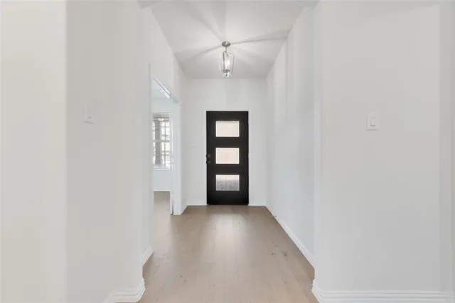 a view of a hallway with wooden floor and a chandelier