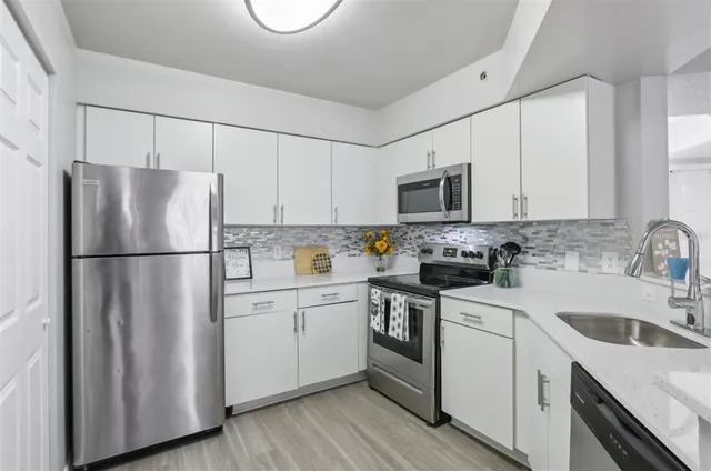 a kitchen with a refrigerator sink and white cabinets