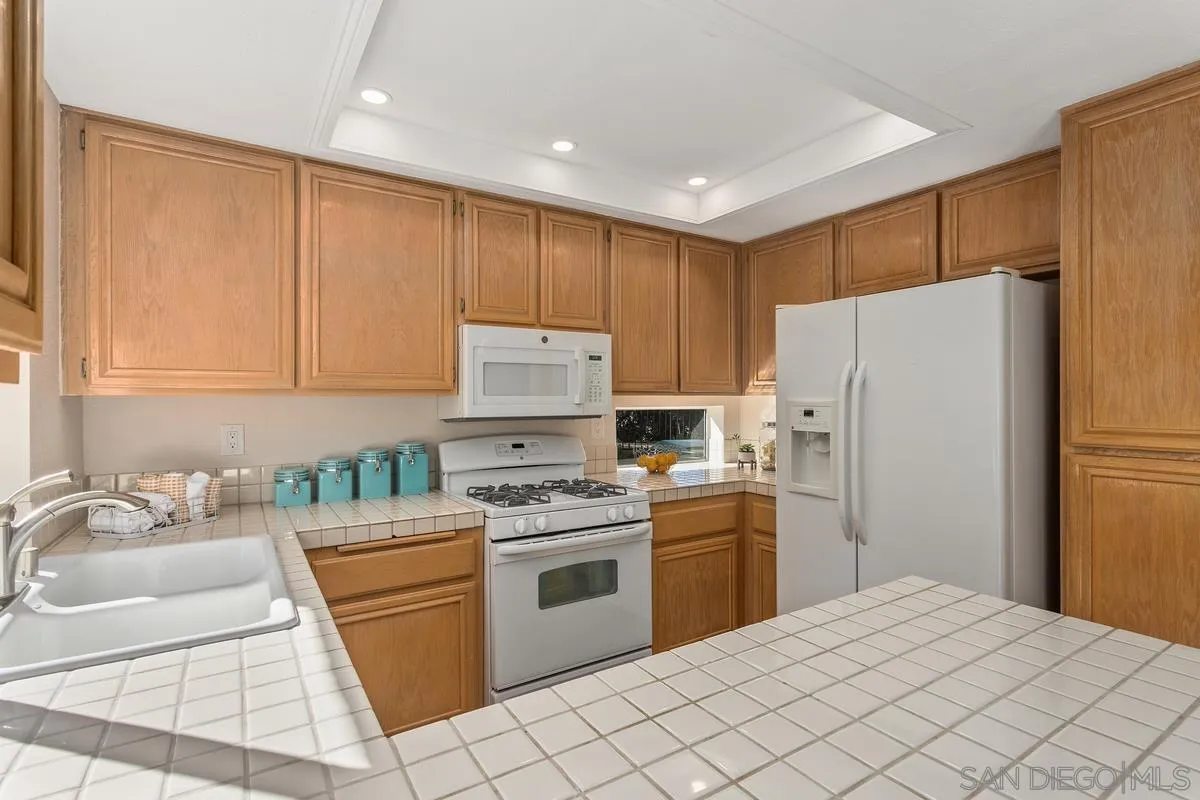 1501 Promontory Ridge Way Vista, CA 92081 - Photo 8 of 22 a kitchen with a white cabinets and white stainless steel appliances