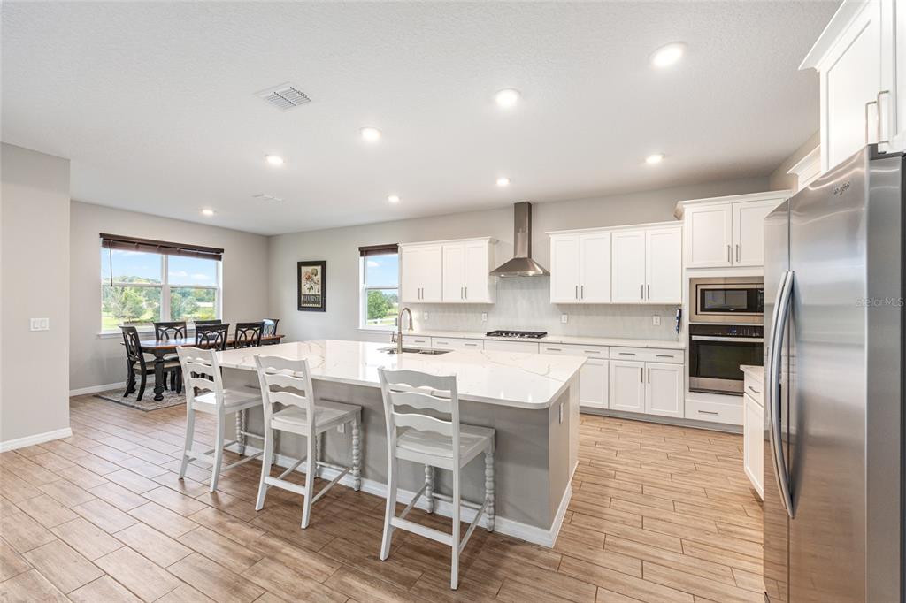 6488 Southwest 78th Court Ocala, FL 34474 - Photo 11 of 40 a kitchen with stainless steel appliances kitchen island granite countertop a refrigerator a stove a dining table and chairs
