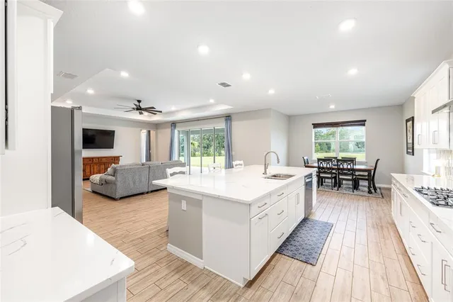 a large white kitchen with a large window a sink and stainless steel appliances