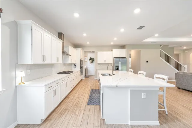 a large kitchen with stainless steel appliances kitchen island a stove a sink dishwasher and a refrigerator with wooden floor