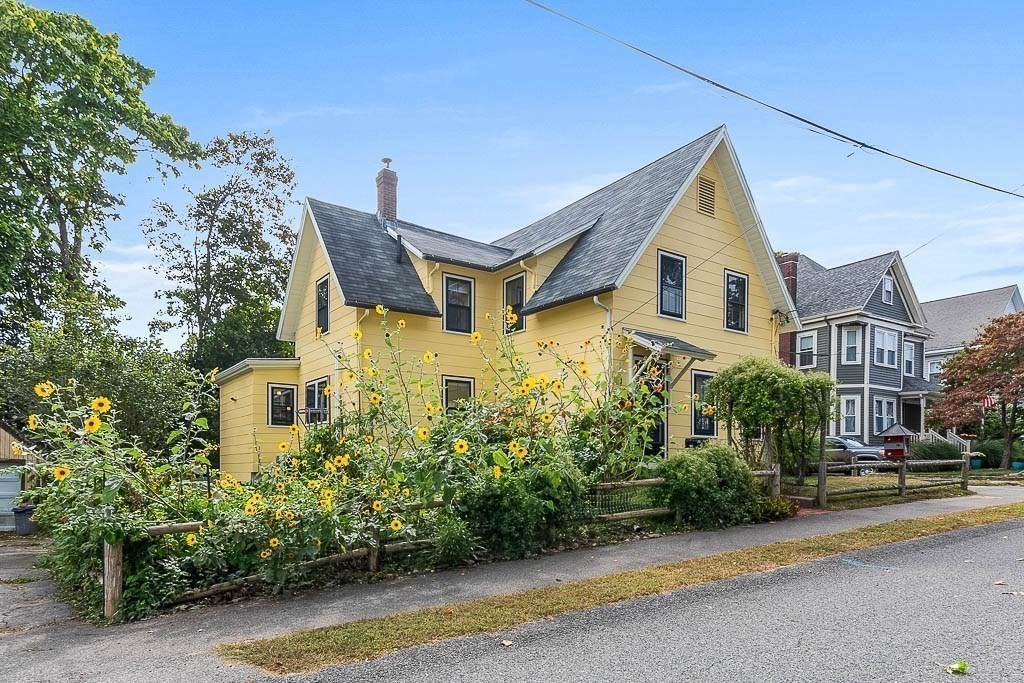 56 Clark Street Dedham, MA 02026 - Photo 2 of 42 a view of a brick house with plants and large trees