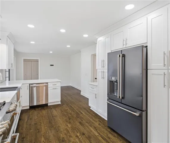 a kitchen with a refrigerator stainless steel appliances wooden floor and cabinets