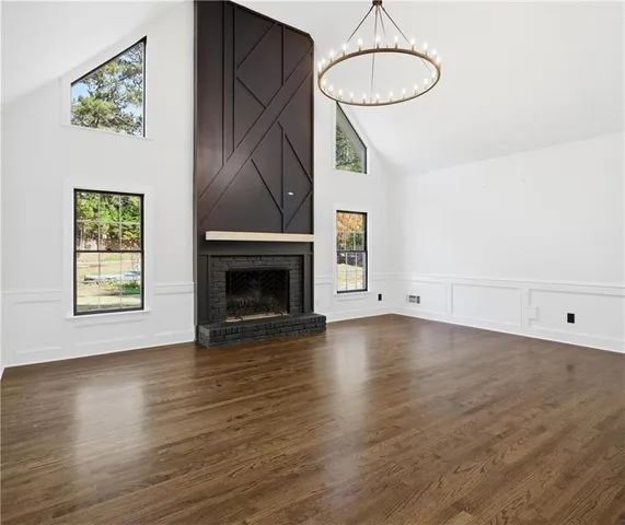 a view of an empty room with wooden floor and a fireplace