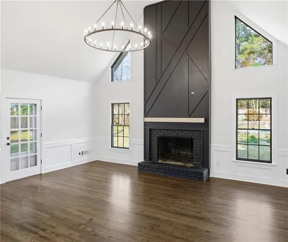 a view of an empty room with wooden floor fireplace and a window
