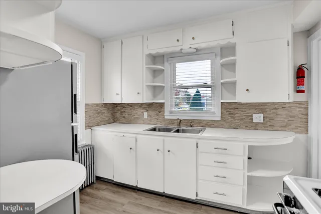 a kitchen with a sink a stove a refrigerator and white cabinets