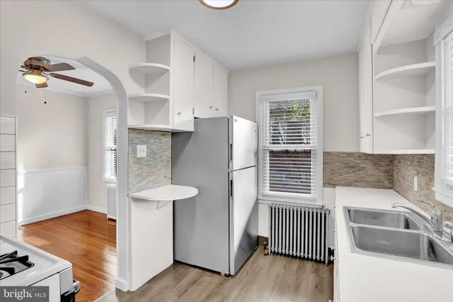 a kitchen with stainless steel appliances granite countertop a refrigerator a sink and white cabinets