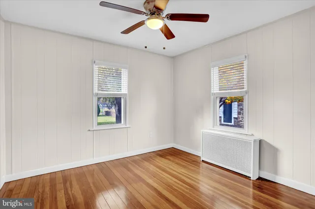a view of an empty room with window and wooden floor