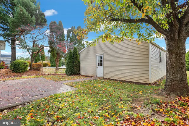 a view of a white house next to a yard and a large tree