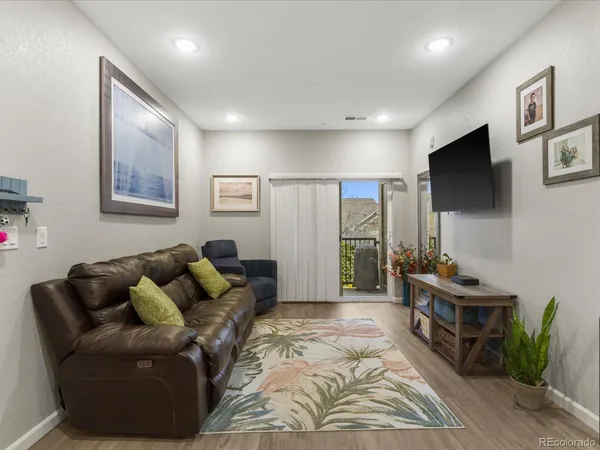 a living room with furniture kitchen view and a wooden floor