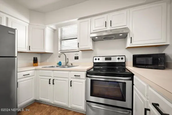 a kitchen with white cabinets and appliances