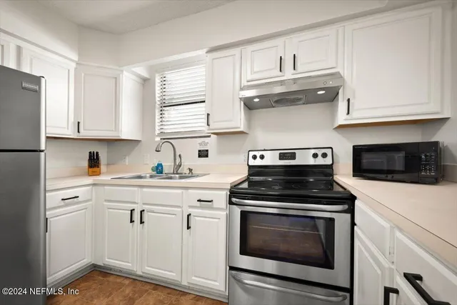 a kitchen with white cabinets and appliances
