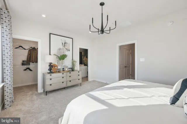 a bedroom with a bed chandelier and dresser