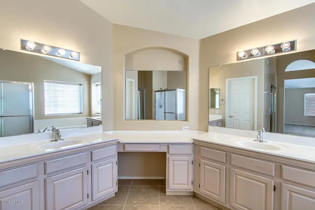 a bathroom with double vanity and a mirror