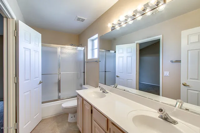 a bathroom with a sink toilet double vanity and shower