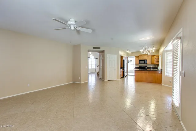 a view of an empty room and kitchen view with wooden floor