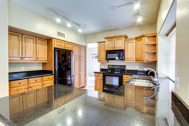 a kitchen with granite countertop a stove top oven a sink dishwasher and a refrigerator with wooden floor