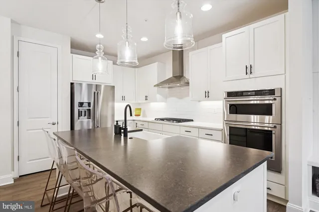 a kitchen with stainless steel appliances granite countertop a sink a stove and a refrigerator