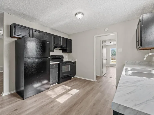 a kitchen with granite countertop a refrigerator and a sink