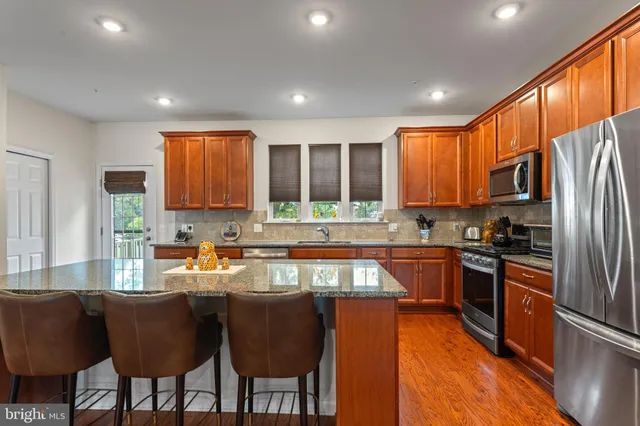 a kitchen with granite countertop a stove top oven a sink dishwasher a dining table and chairs with wooden floor