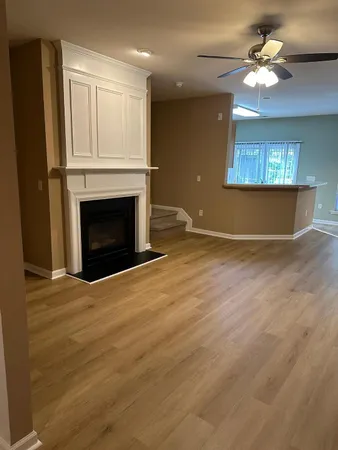 a view of an empty room with a fireplace and a chandelier fan