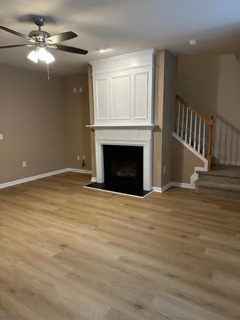 a view of an empty room with wooden floor fireplace and a window