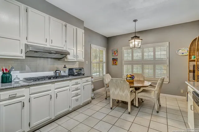 a kitchen with granite countertop white cabinets dining table and chairs