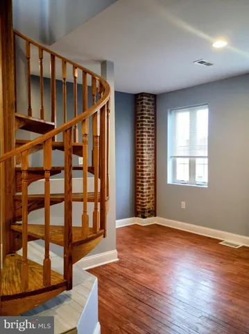 a view of an empty room with wooden floor and windows